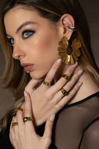 Mujer con anillos de oro con piedras de diferentes colores y aretes llamativos y de diferentes estilos
