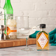 Gibson cocktail in a coupe with a bottle of The Bitter Housewife Grapefruit Bitters standing next to the glass