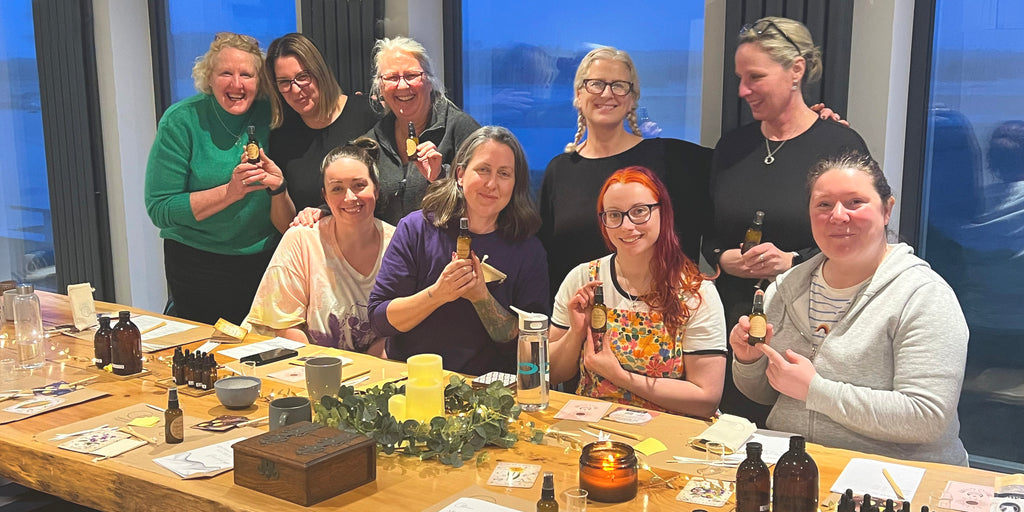 Group of joyful people participating in a wellness workshop creating custom aromatherapy blends with essential oils, surrounded by natural elements and workshop materials, conveying a sense of community and wellbeing