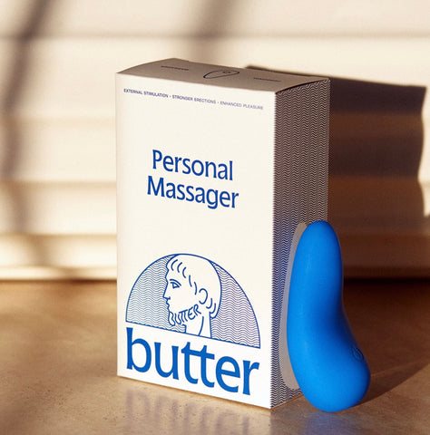 Moody image of the Personal Massager by Butter Wellness propped up against the packaging.
