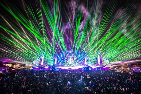 image of a rave at night with colourful laser beaming into the sky