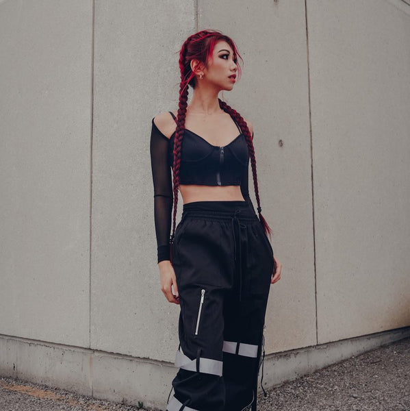 red hair model wearing a mesh bustier and reflective joggers as her rave outfit