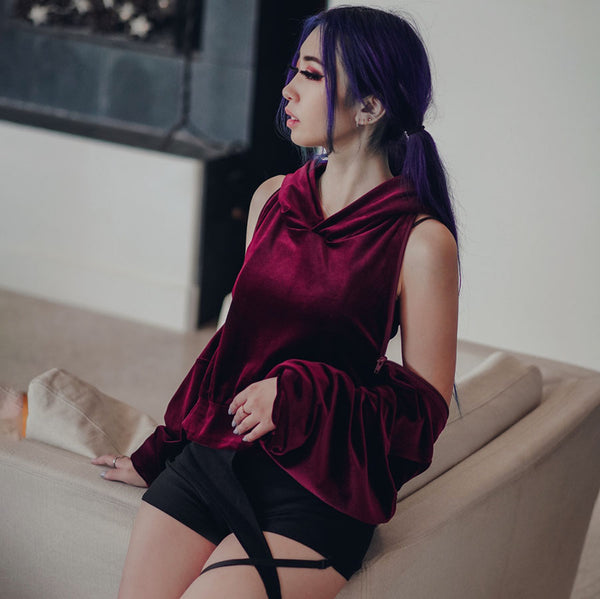 red velvet open back hoodie with purple hair model leaning on couch