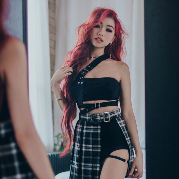 cross strap waist strap crop top and plaid slit skirt on red hair model looking in the mirror