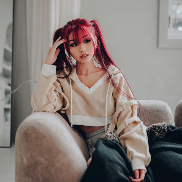 shoyu beige strap hoodie with red hair model sitting on a couch