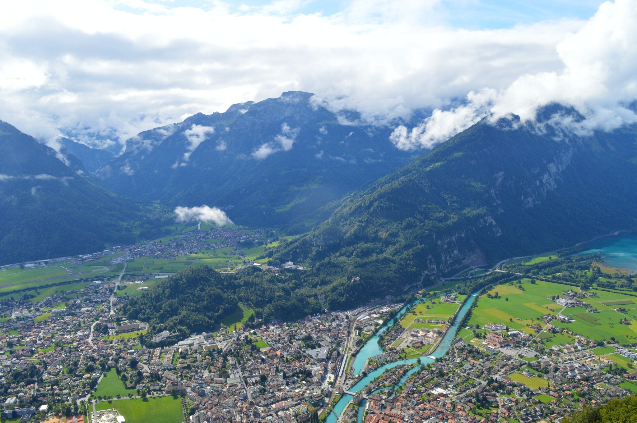 Bird's eye view of Interlaken, Switzerland with blue water running through the middle of a city in a valley surrounded by mountains