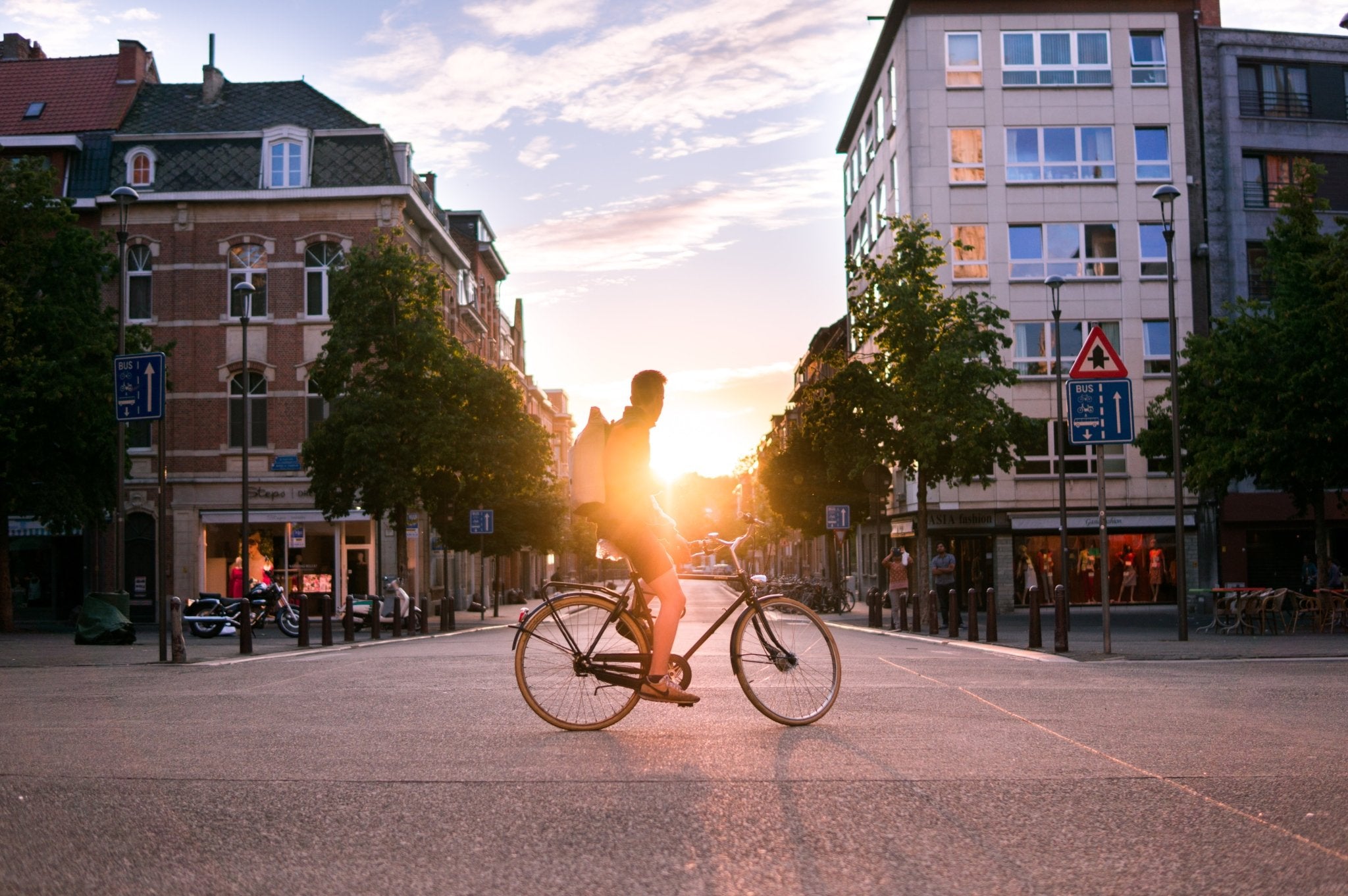 Main sitting on a bike with the sunset behind him in a city in Belgium