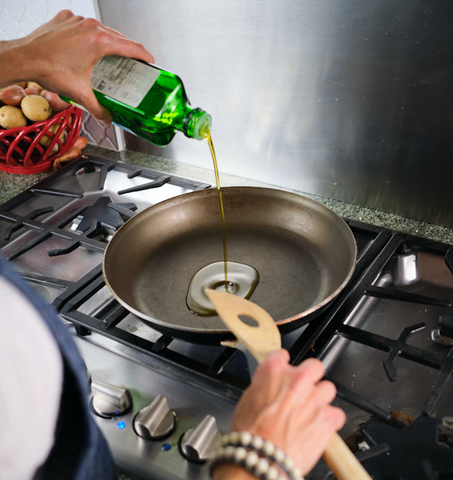 Pouring olive oil in a non-stick pan in preparation for cooking
