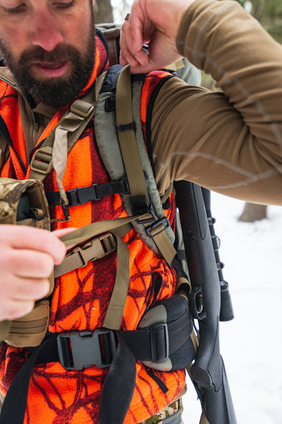 Hunter in orange and camo using his rifle sling's quick-release strap