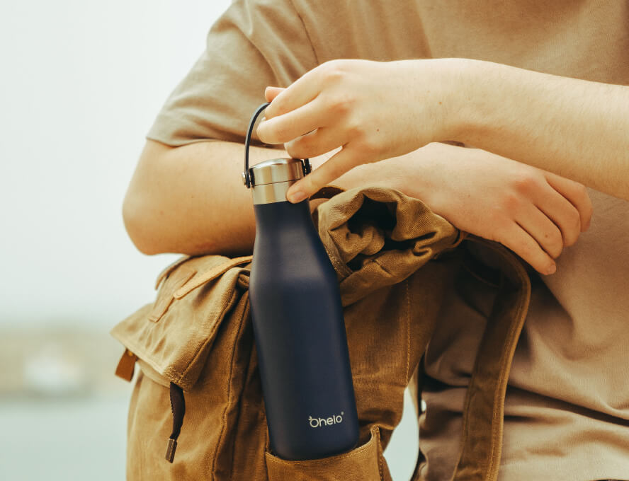 Man lifting Ohelo reusable water bottle in Oxford Blue from travel bag
