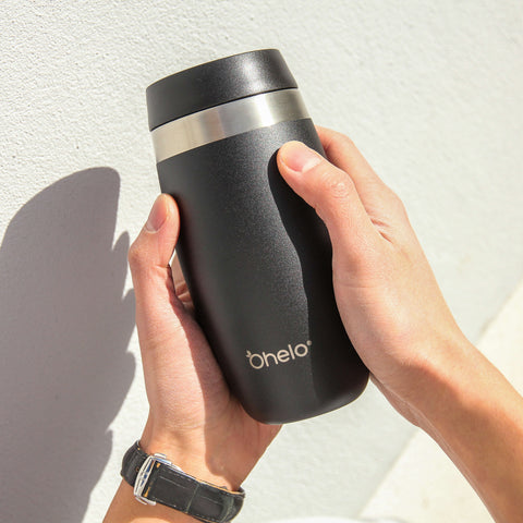 Ohelo black tumbler held in hands against a white background