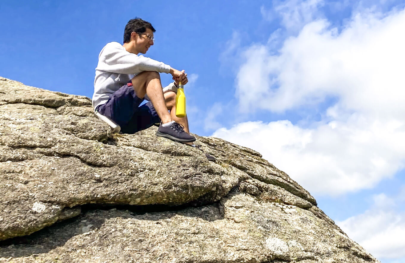 Man sitting on a rock face with a yellow Ohelo water bottle