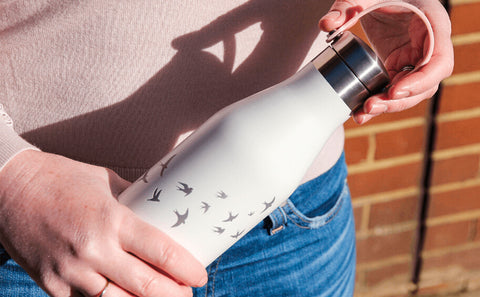 Woman holding Ohelo white swallows insulated reusable bottle 