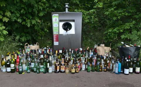 glass recycling point with glass bottles on the ground
