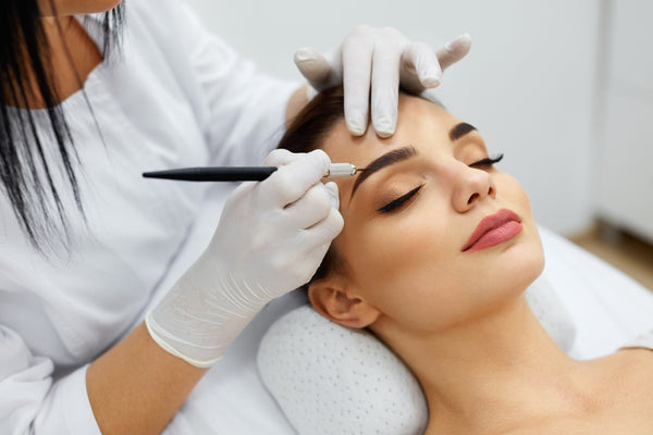 beautician performing eyebrow makeup tattoo