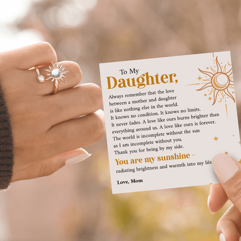 Female model wearing sunshine fidget ring on her left ring finger while holding a heart warming message card