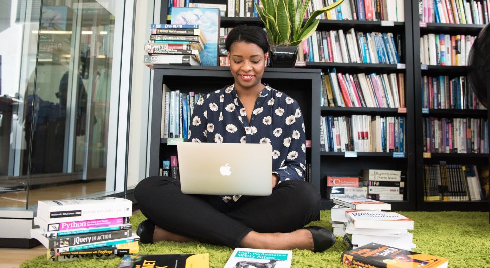 A woman sitting at the floor while in front of her laptop