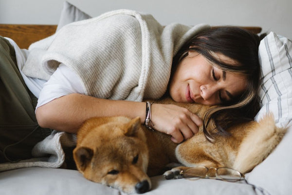 Woman and dog sleeping in bed