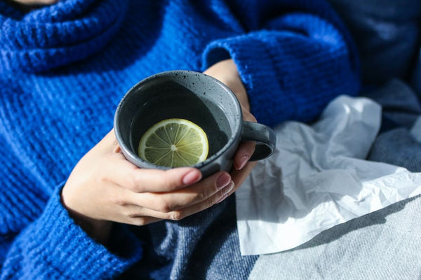 Woman in royal blue sweater holding mug of tea and honey