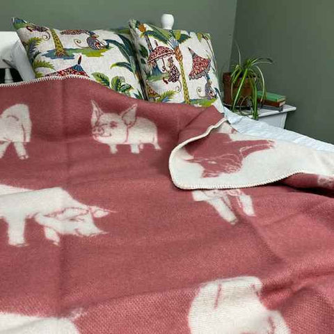 Pink Pig wool blanket on a bed