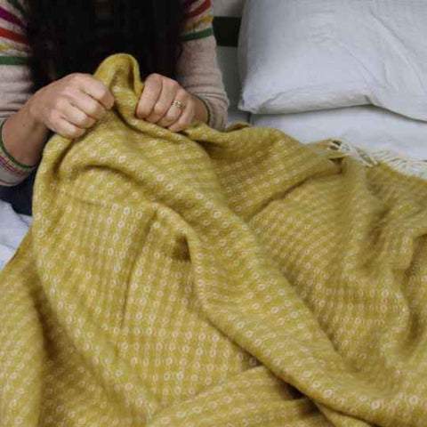 Mustard yellow wool blanket on a bed