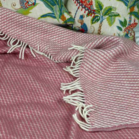 Pink wool blanket on a bed.