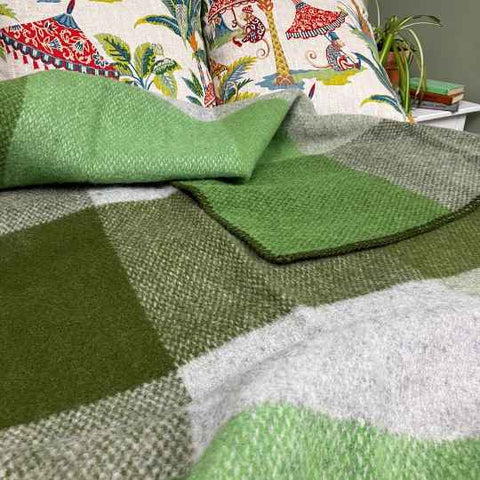 Green woollen blanket on a bed