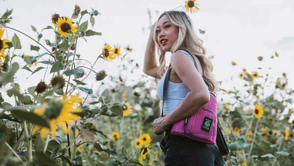 Woman standing in field of sunflowers with magenta Club Kid mini backpack on