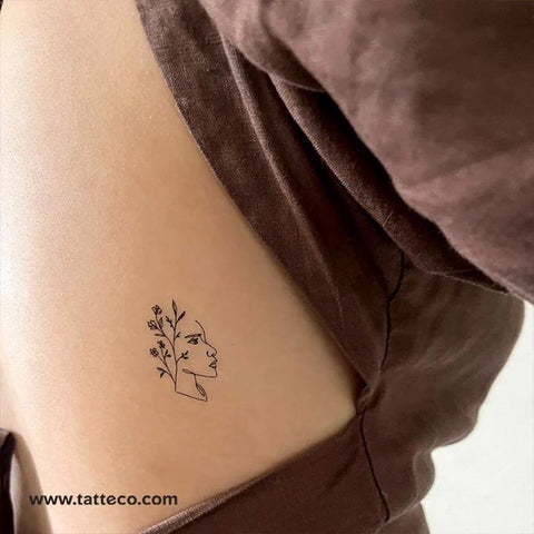 Female figure tattoo: Fine line outline of woman's face with foliage