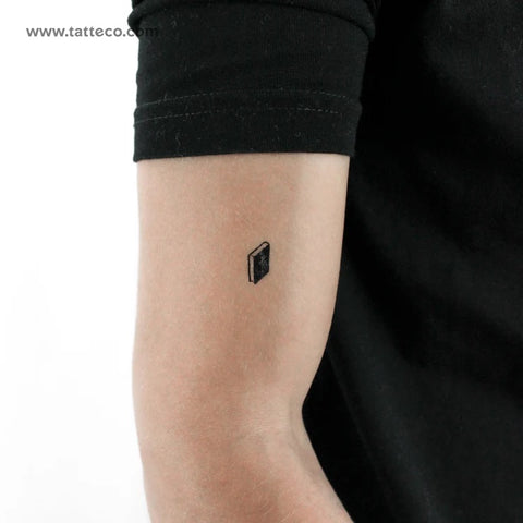 Minimalist Christian Tattoos: A small black bible tattoo