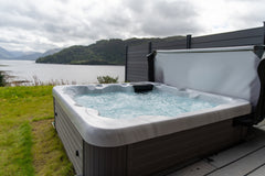 Hot tub by the side of a lake with a fence for privacy