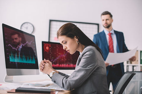 Image of a young businesswoman and businessman computer working with papers and charts on computer monitors in the office