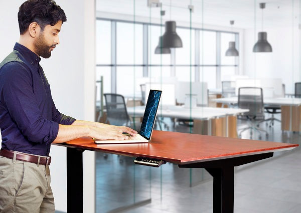 A person at a standing desk and looking at a computer