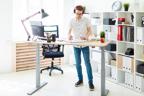 Photo of a young man in headphone he is working with documents for a standing desk 