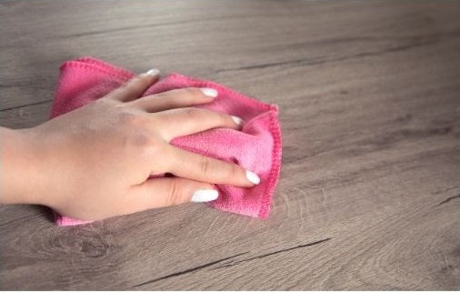 Cleaning a wood tabletop with a soft sponge