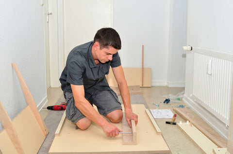 Photo of a man mounting furniture with a screwdriver