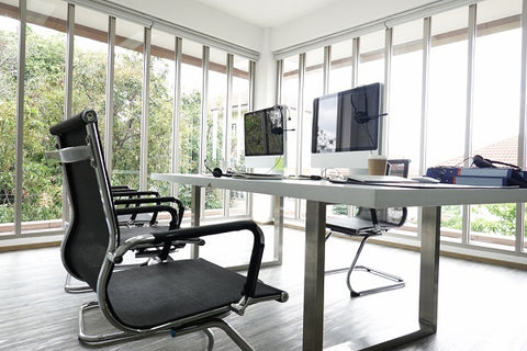 Photo of interior of a business office with a glass wall. There are armchairs, table and two computers in the room