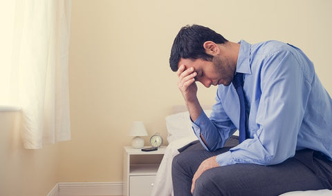 Photo of a man sitting on his bed in a bedroom at home