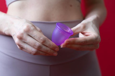 Ruby Cup image of a woman holding a purple menstrual cup