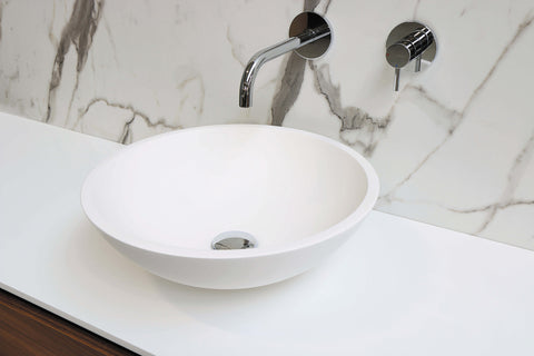 07_Image of a pristine sink on a white surface in front of a marble wall