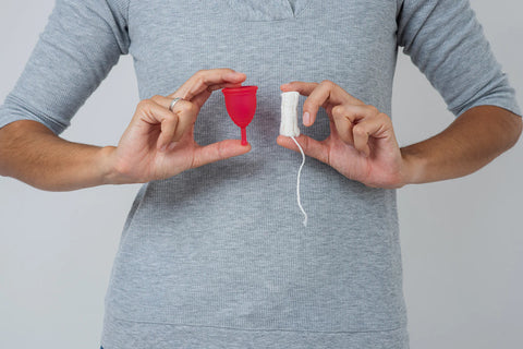 person holding a tampon and a menstrual cup