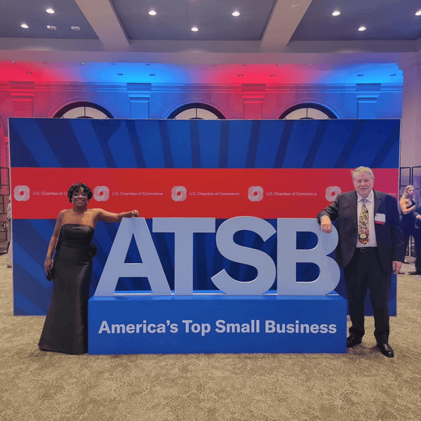 Lily and Stan in front of the America's Top Small Business Logo