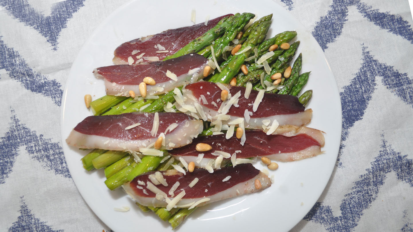 Roasted asparagus on a plate with duck breast prosciutto.