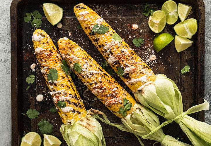 Grilled corn on the cob served with lime and cheese.