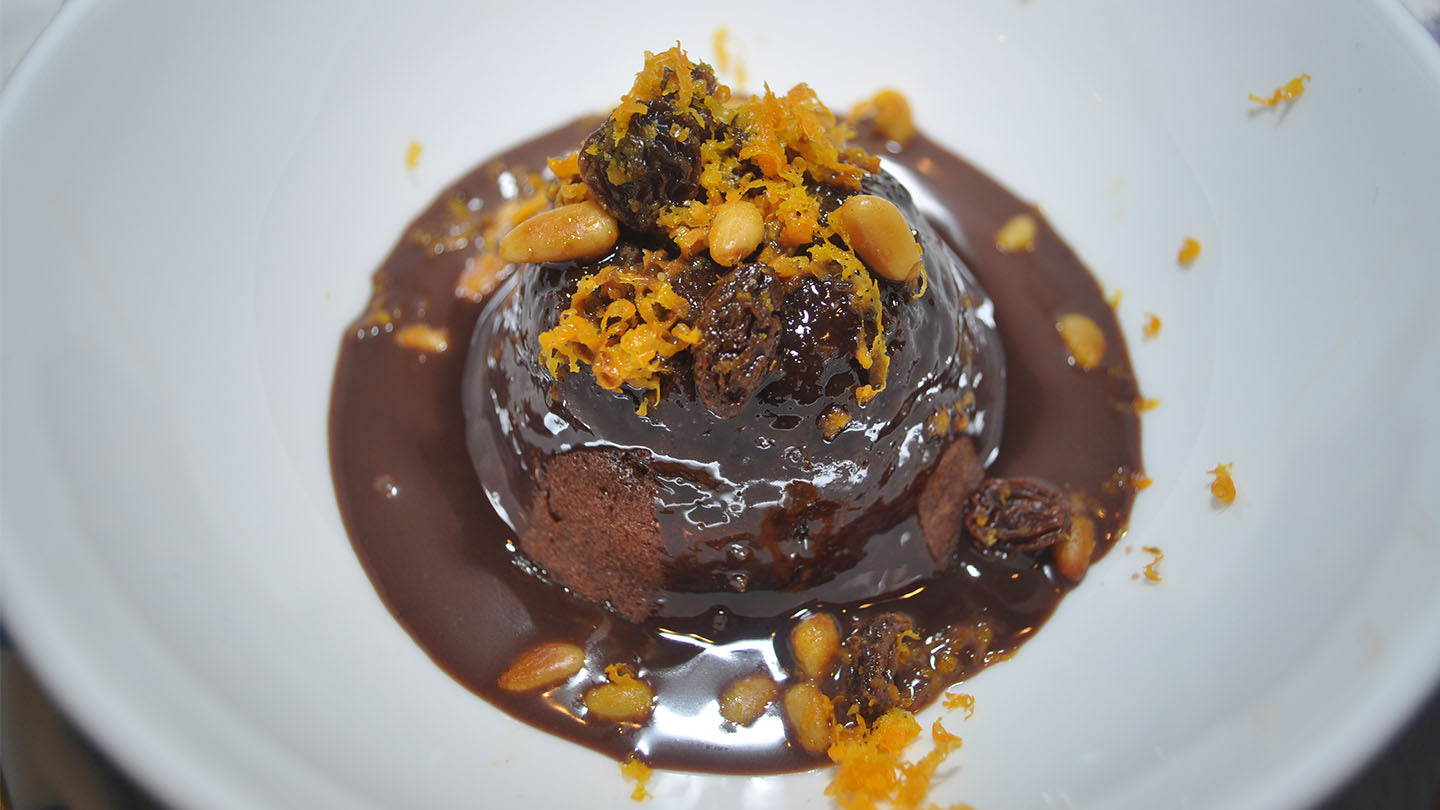 Chocolate orange spoon cake topped with raisins, nuts, and fresh orange zest.
