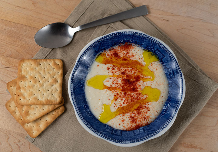 Cauliflower soup made with cream and cheese, seasoned with paprika on top.