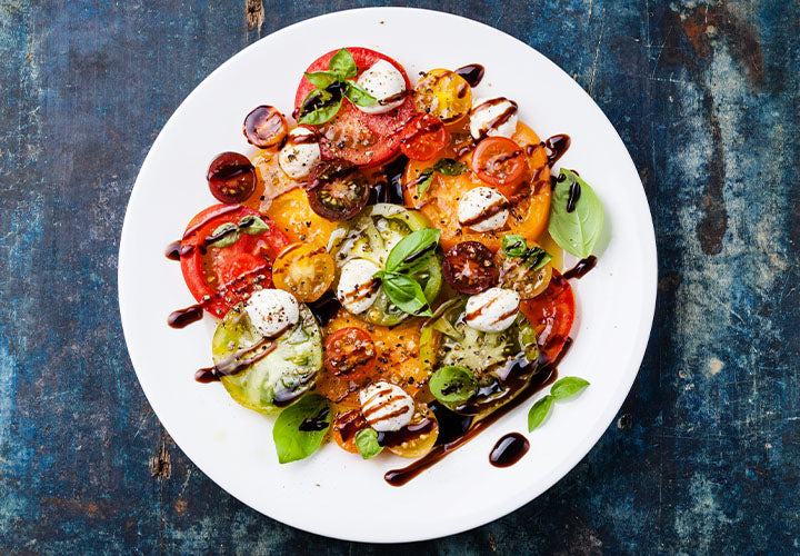 Tomato salad with fresh mozzarella cheese, basil leaves, and balsamic vinaigrette.