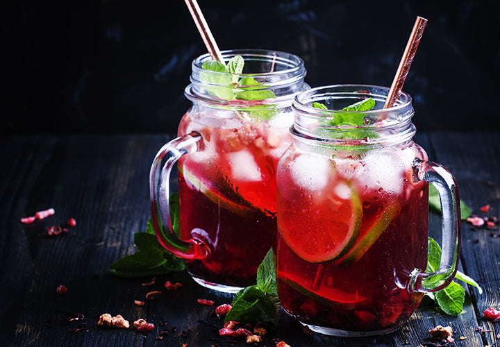 Mason jar mug filled with fizzy hibiscus drink with lime juice and fresh mint.