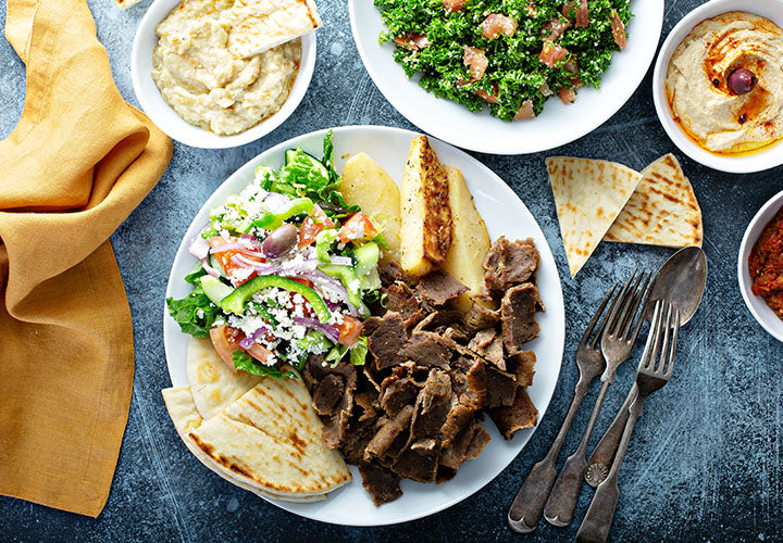 Picture of delicious gyro meat on a place with salad and pita bread.