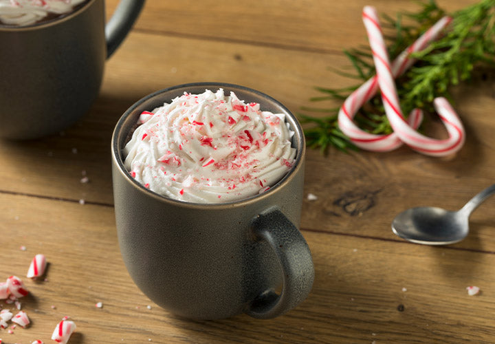 Hot cocoa made with peppermint extract and whipped cream and candy canes.